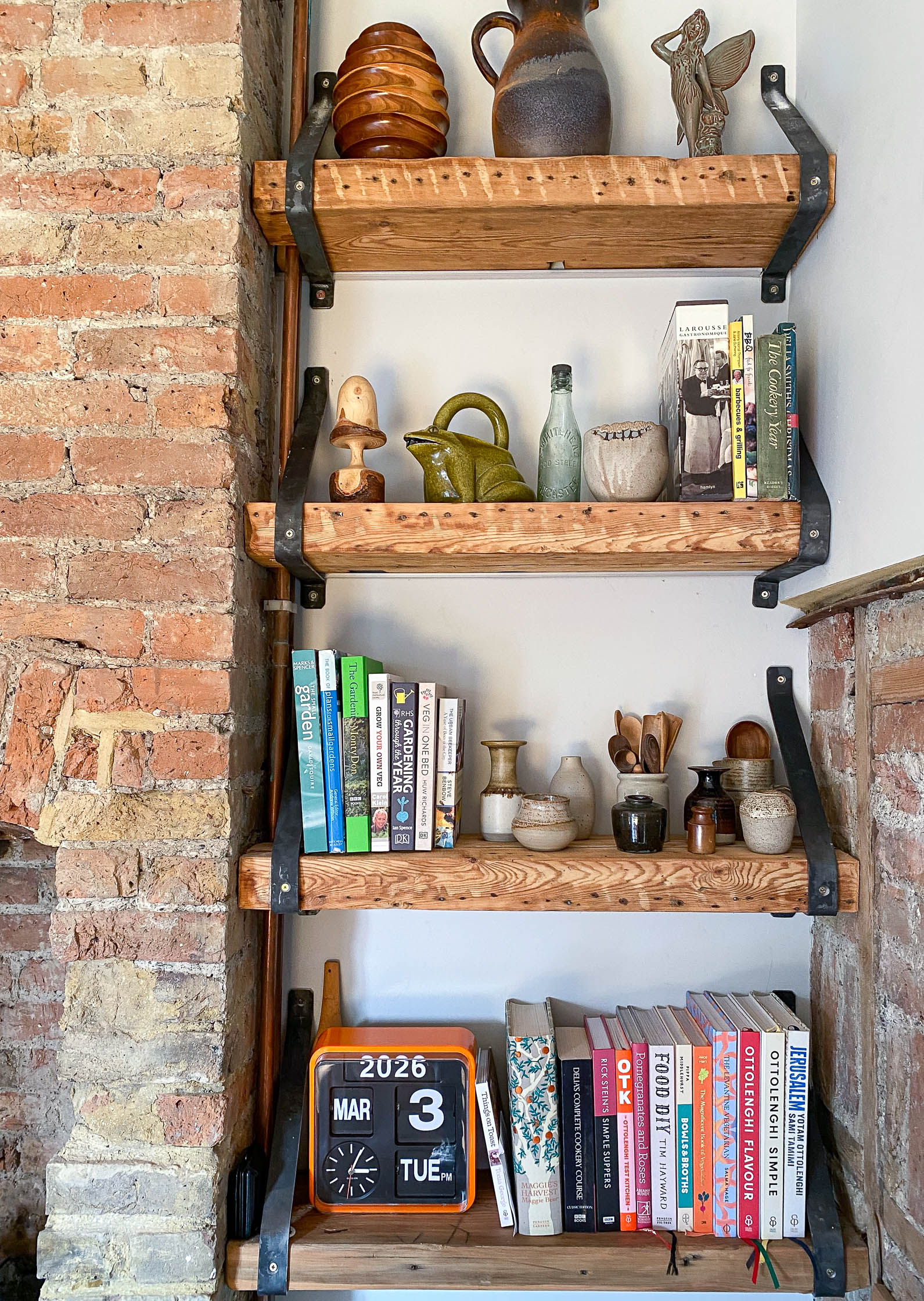 Wooden shelves & steel brackets by exposed chimney stack wood stove